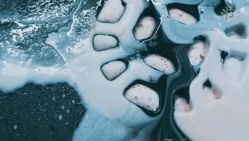 Valkoinen pesuvaahto valuu mustan vanteen puolapuiden välissä
